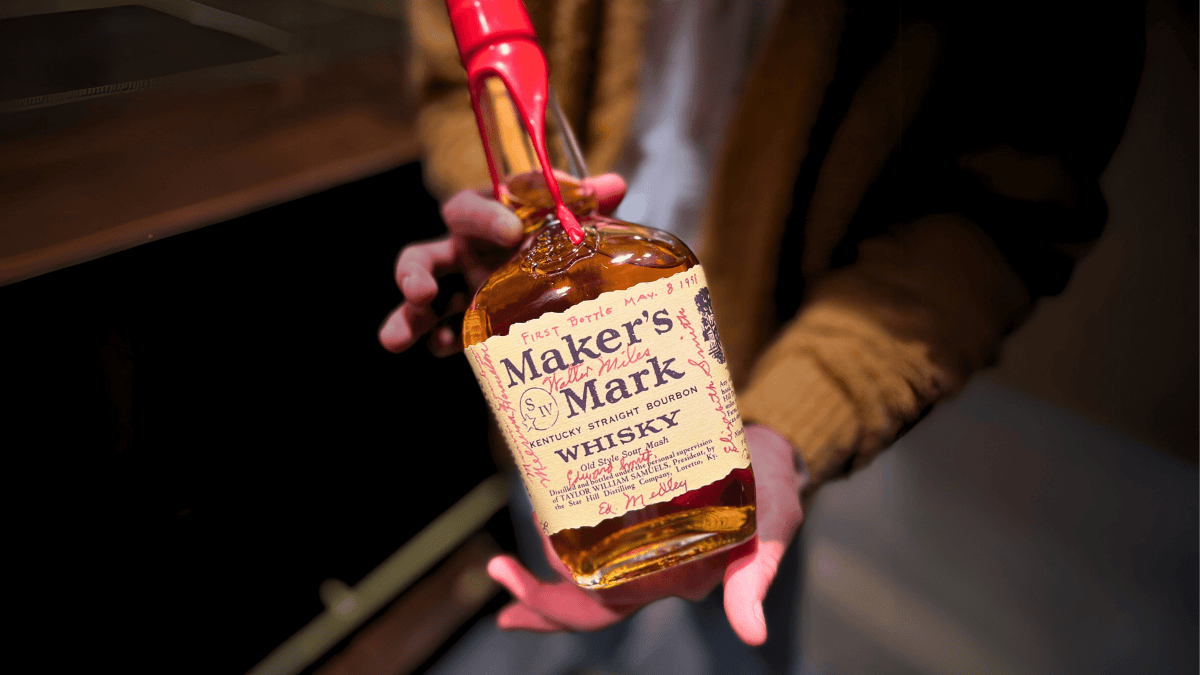 Hands holding up Maker's Mark whisky bottle